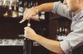 Bartender concentrated on uncork of elite drink at bar counter.