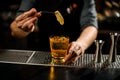 Bartender decorated the yellow color alcoholic cocktail drink with a ginger slice with tweezers