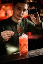 Bartender decorates glass with cold cocktail with chocolate candy on stick and sprinkles with powdered sugar Royalty Free Stock Photo