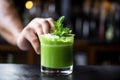 bartender garnishing iced matcha cocktail at a bar