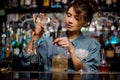 Bartender girl pouring to the steel jigger an alcoholic drink on the bar counter