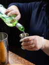 A bartender with gloves pours vermouth from a bottle into a stainless steel measuring cup Royalty Free Stock Photo