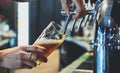 Bartender hand at beer tap pouring a draught beer in glass