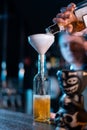 bartender hand pouring yellow whiskey to bottle