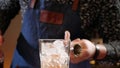 Bartender hands measuring cocktail ingredient with jigger then pouring it in a glass