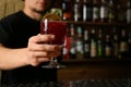 Bartender holding glass of alcoholic cocktail in bar, closeup. Space for text Royalty Free Stock Photo