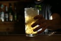 Bartender holding glass of fresh alcoholic cocktail at bar counter, closeup Royalty Free Stock Photo