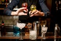 Bartender holds bottles with liquor and adds it to glass with cocktail Royalty Free Stock Photo