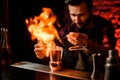 Bartender holds tweezers with spikelet over metal cup and makes fire flame.