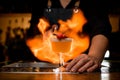 Bartender impressively sets fire on glass with whiskey sour cocktail decorated with two small red hearts