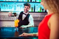 Bartender looking at woman while pouring cocktail in glass Royalty Free Stock Photo