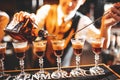 The bartender makes cocktails with liquor, using a bar spoon. layered cocktails. Bar counter. Atmospheric photo with warm tinting.