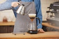 Bartender making alternative coffee using manual drip brewer, pouring water.