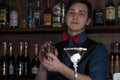 Bartender making drink with sheker at counter with glass in bar