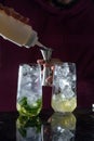 bartender making summer alcoholic cocktails mojito with rum, mint, lime and ice, bar tools, gray background, selective Royalty Free Stock Photo