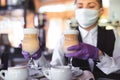 Bartender in medical mask and gloves makes latte coffee