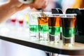 Bartender pouring alcoholic cocktail in shot glasses on bar