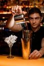 Bartender pouring alcoholic drink from copper mug into steel shaker cups Royalty Free Stock Photo