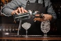 Bartender pouring alcoholic drink into a glass using a jigger to prepare a cocktail