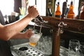 Bartender pouring beer from tap into glass in bar, Royalty Free Stock Photo