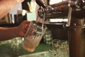 Bartender pouring beer from tap into glass in bar Royalty Free Stock Photo