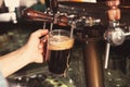 Bartender pouring beer from tap into glass in bar Royalty Free Stock Photo