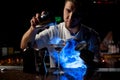 Bartender pouring a brown alcoholic drink from the steel shaker to the glass under blue light Royalty Free Stock Photo
