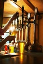 Bartender pouring foamy lager beer into glass from tap, pub interior. Enjoying a cold drink Royalty Free Stock Photo
