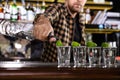 Bartender pouring Mexican Tequila into shot glasses at bar counter
