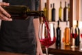 Bartender pouring red wine from bottle into glass in bar Royalty Free Stock Photo