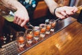 Bartender pouring strong alcoholic drink into small glasses on bar, shots. Royalty Free Stock Photo