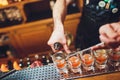 Bartender pouring strong alcoholic drink into small glasses on bar, shots. Royalty Free Stock Photo