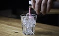 Bartender pouring a strong alcoholic drink into small glasses with ice. Red alcoholic drink. Barman is preparing a cocktail Royalty Free Stock Photo