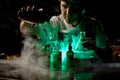 Bartender pouring a transparent alcoholic drink from the steel shaker to the glass under green light Royalty Free Stock Photo