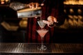 Bartender pourring a Cosmopolitan from a shaker to a glass