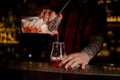 Bartender pourring a Sazerac cocktail from the glass measuring c