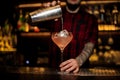 Bartender pourring a Sicilian Tonic cocktail from the steel shaker