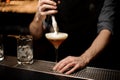 Bartender pours an alcohol cocktail adding foam