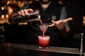 Bartender pours alcohol drink using shaker and sieve