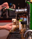 Bartender pours cold beer into glass from tap