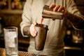 Bartender pours tomato juice from one steel shaker glass into another glass Royalty Free Stock Photo