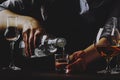 The bartender pours the vodka or tequila in small shot glass on the old bar counter. Vintage wooden background in pub or bar, Royalty Free Stock Photo