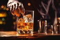 The bartender pours whiskey into a glass with ice on the bar counter. close-up. Blurred background. Elite alcoholic drink Royalty Free Stock Photo