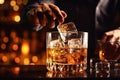 The bartender pours whiskey into a glass with ice on the bar counter. close-up. Blurred background. Elite alcoholic drink Royalty Free Stock Photo