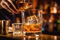 The bartender pours whiskey into a glass with ice on the bar counter. close-up. Blurred background. Elite alcoholic drink Royalty Free Stock Photo