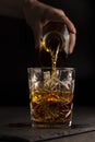The bartender pours whiskey or rum into a glass,