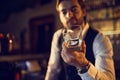 Bartender presenting an empty whiskey glass in dim bar interior Royalty Free Stock Photo