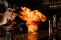 Bartender professionally sprinkles on glass with cocktail and sets it on fire. Royalty Free Stock Photo