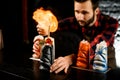 Bartender makes fire over ceramic cup with cocktail. Royalty Free Stock Photo