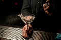 Bartender spraying drink with branch of white leaves